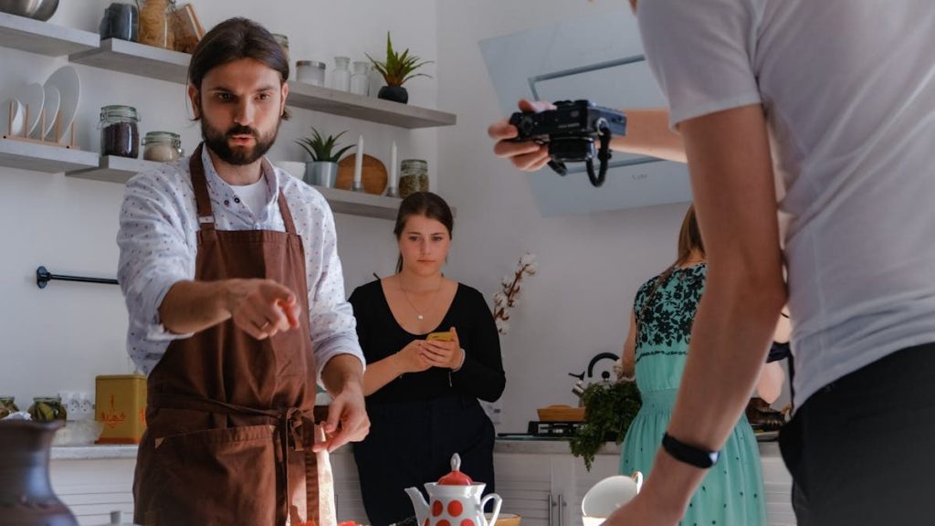Chef being photographed during a cooking session in a modern indoor kitchen.
